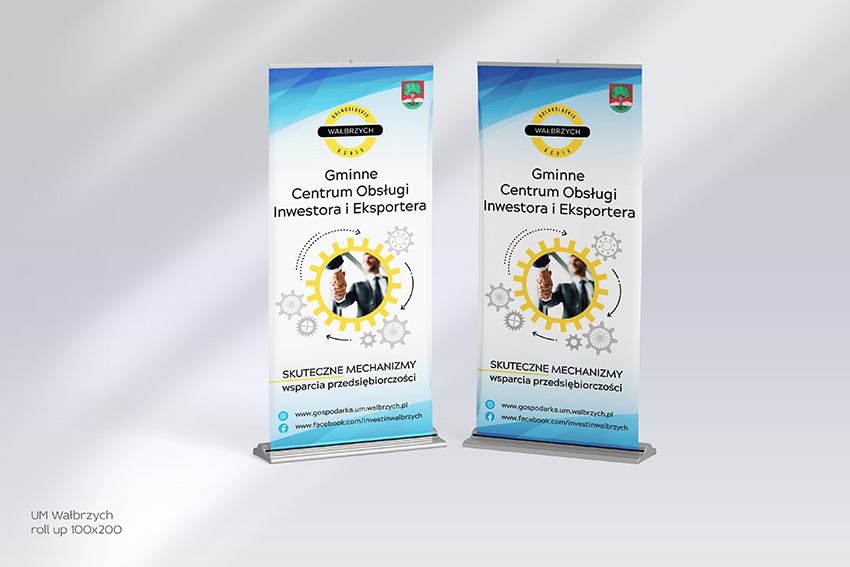 Dwa identyczne roll-upy reklamowe 100x200 dla Gminnego Centrum Obsługi Inwestora i Eksportera w Wałbrzychu, z logo miasta i hasłem 'Skuteczne mechanizmy wsparcia przedsiębiorczości', ustawione...