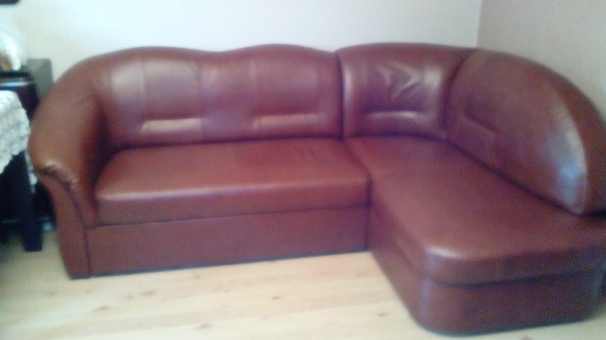 Brązowy narożnik z ekoskóry w salonie, widoczny fragment podłogi z jasnych paneli.