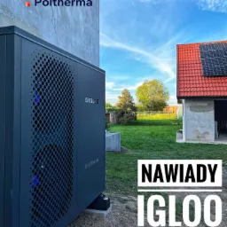 Zewnętrzna jednostka pompy ciepła IGLOO MultiTherma zainstalowana przy ścianie budynku, w tle budynek z czerwonym dachem i panelami słonecznymi, widoczne elementy instalacji na zewnątrz.