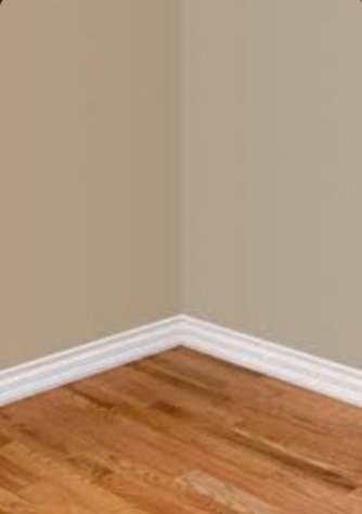 Wnętrze pokoju po remoncie: parkiet z drewna, beżowe ściany i biała listwa przypodłogowa w rogu pomieszczenia.