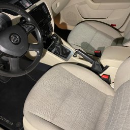 Car Serwis Janki Mateusz Zieliński Maciej Zielkowski Spółka Cywilna - Wnętrze samochodu Skoda Octavia z beżową tapicerką, widok na przednie fotele, deskę rozdzielczą i kierownicę z logo marki.