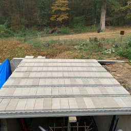 Atlantis b&b - Budowa stropu Teriva w Nowęcinie, widoczne elementy stropowe ułożone na ścianach fundamentowych, w tle drzewa i niebieska plandeka.