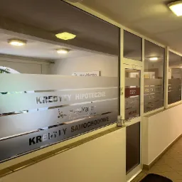 Wejście do biura firmy finansowej z naklejonymi na szybie napisami: Kredyty Hipoteczne, Kredyty Samochodowe oraz logo Grupa Maestro