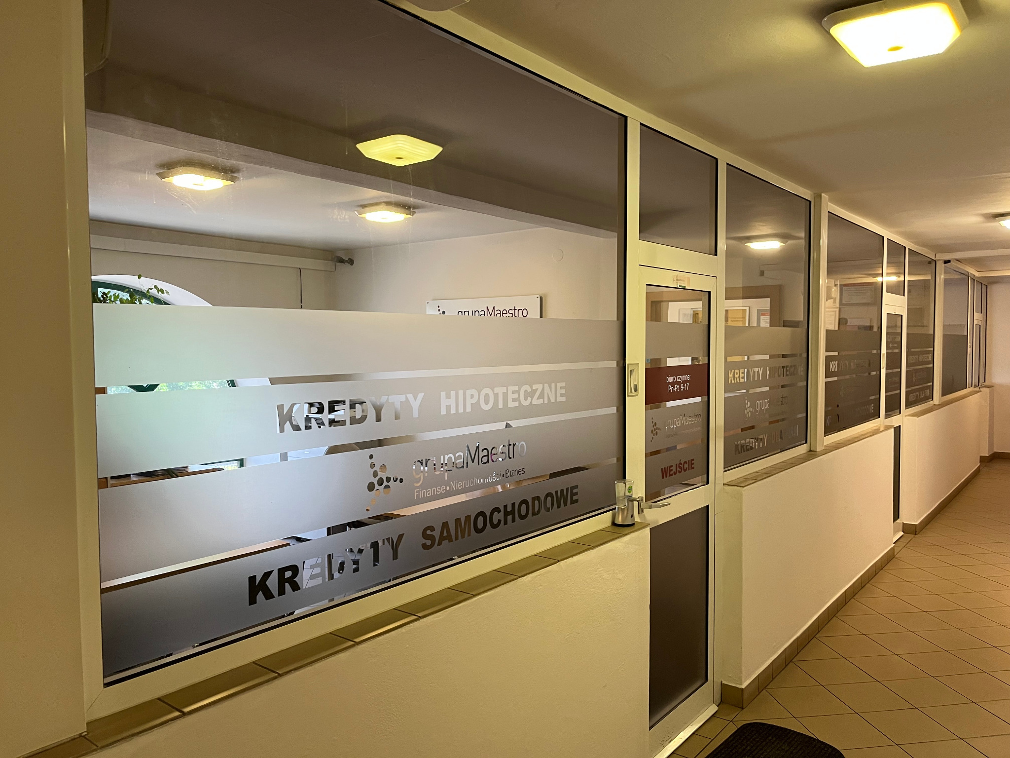 Wejście do biura firmy finansowej z naklejonymi na szybie napisami: Kredyty Hipoteczne, Kredyty Samochodowe oraz logo Grupa Maestro