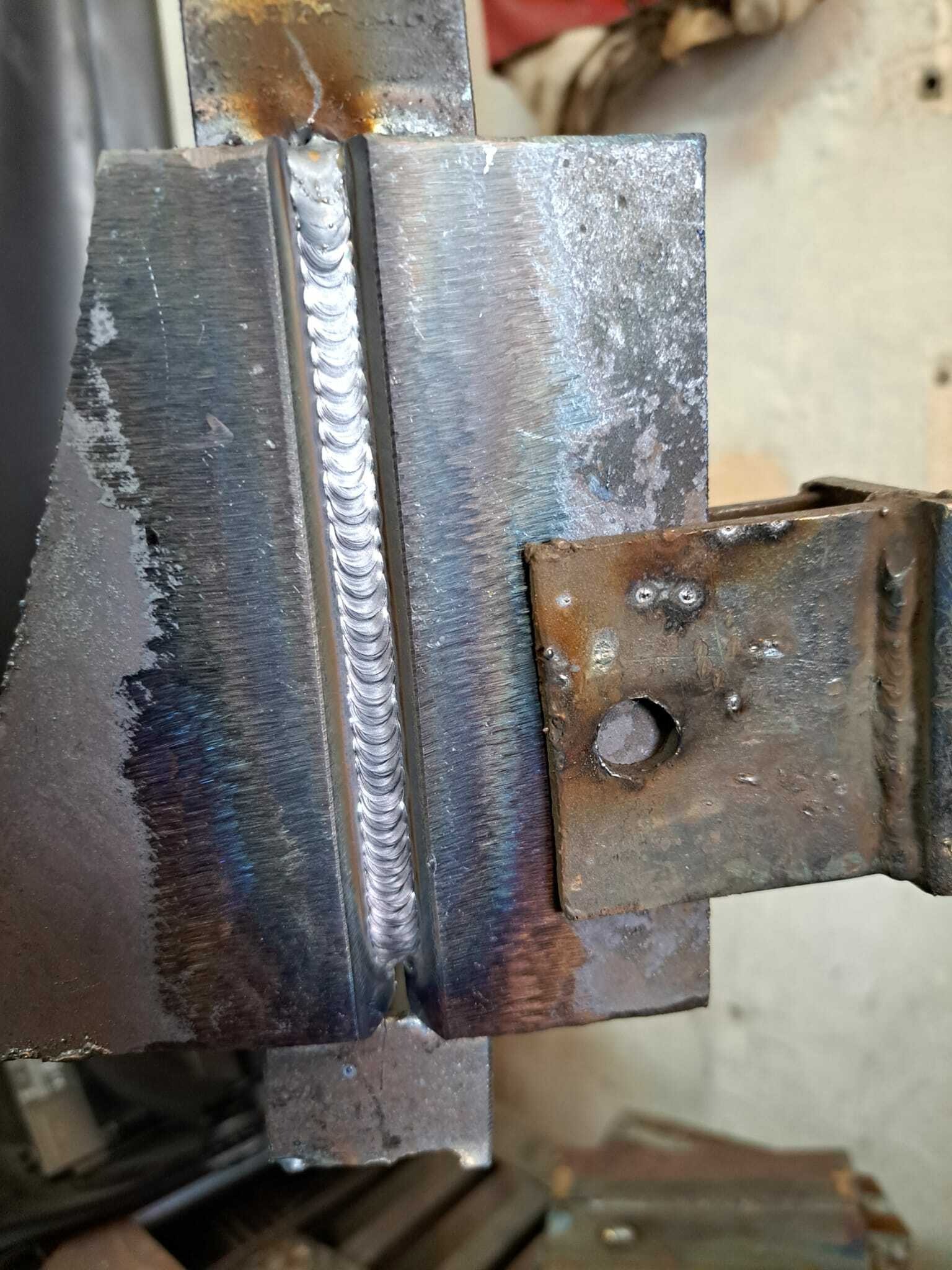 Spoina spawalnicza na elementach stalowych, widoczne ślady obróbki termicznej i przebarwienia metalu.