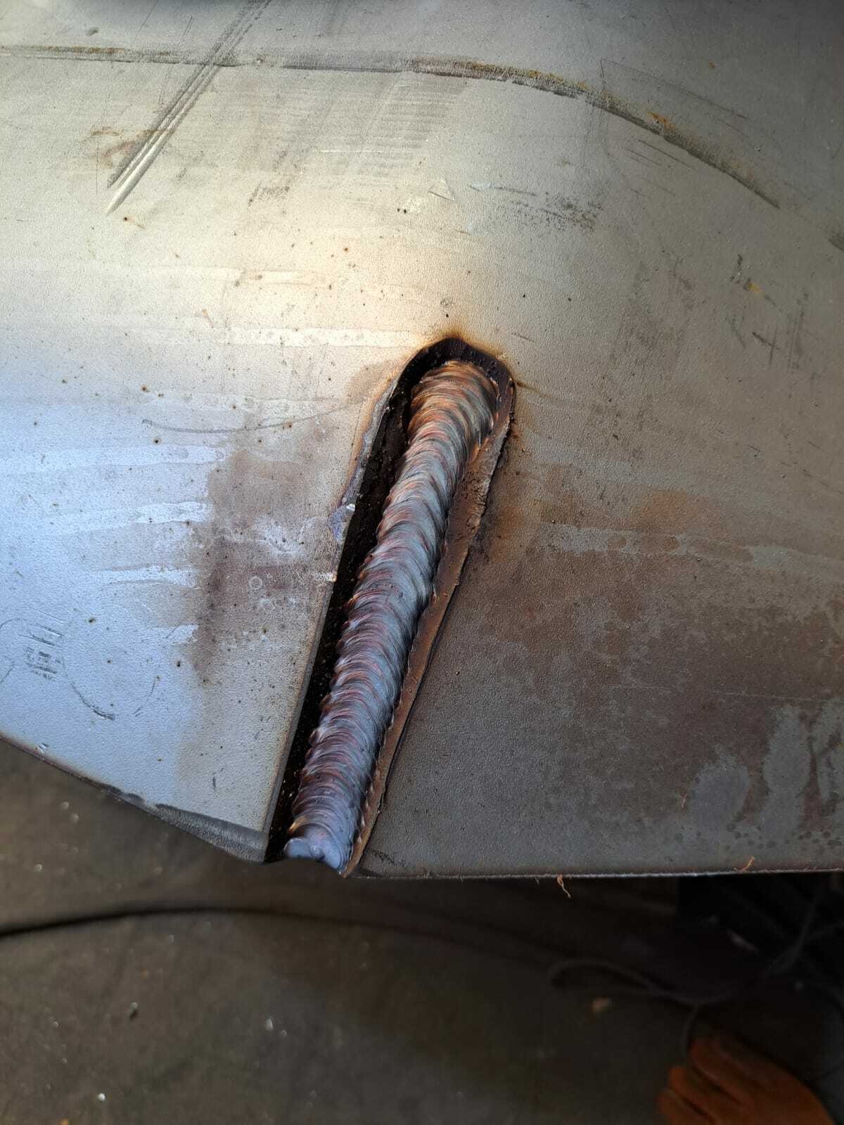 Spoina pachwinowa wykonana metodą spawania łukowego na arkuszu metalu, widoczne ślady po procesie spawania i delikatne przebarwienia cieplne.