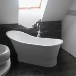 Nowoczesna łazienka na poddaszu z wolnostojącą białą wanną, umywalką nablatową o zaokrąglonym kształcie i ciemnoszarą mozaiką na ścianie.