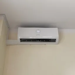 Biała jednostka wewnętrzna klimatyzacji marki Bosch zamontowana na kremowej ścianie, widoczny wyświetlacz temperatury 16 stopni Celsjusza.