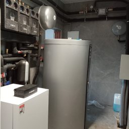 Jar-Mich jarosław Sokołowski Michał Niedźwiecki s.c. - Szara kotłownia z instalacją grzewczą, zbiornikiem buforowym i orurowaniem pod sufitem, widoczne elementy marki Viessmann.