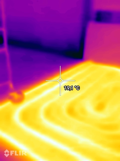 Termowizja podłogowego ogrzewania, widoczne rozłożenie ciepła na powierzchni, temperatura 19,1°C.