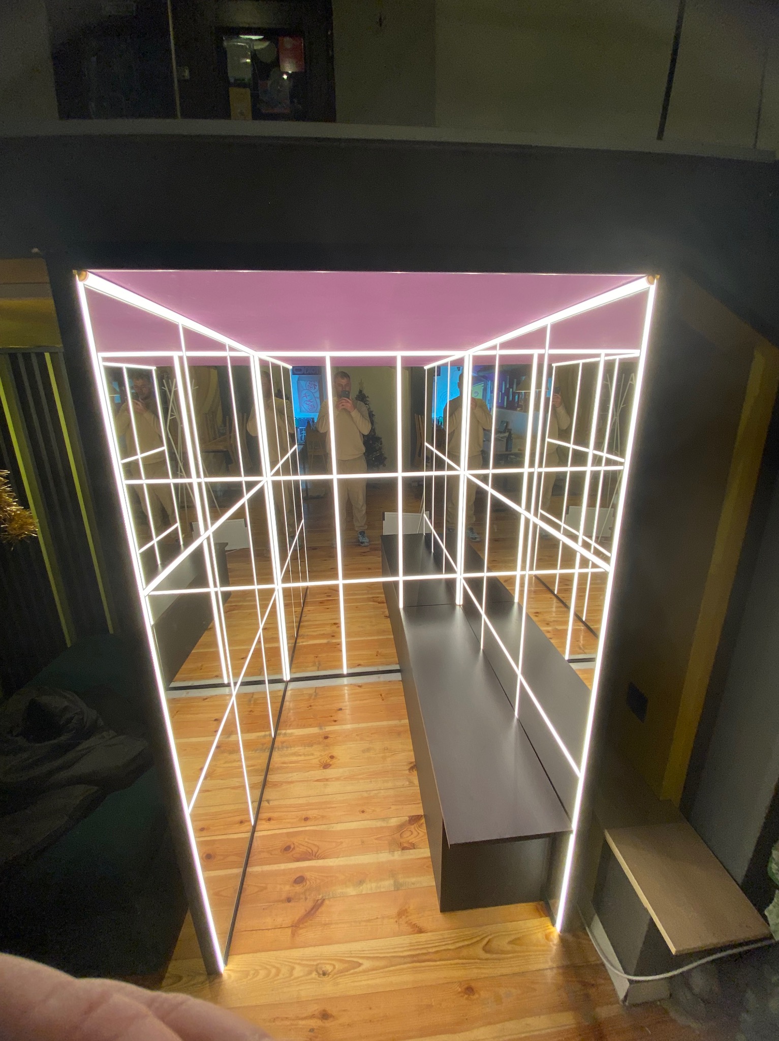 Nowoczesna garderoba z lustrzanymi ścianami i podświetleniem LED, odbicie osoby robiącej zdjęcie, drewniana podłoga.