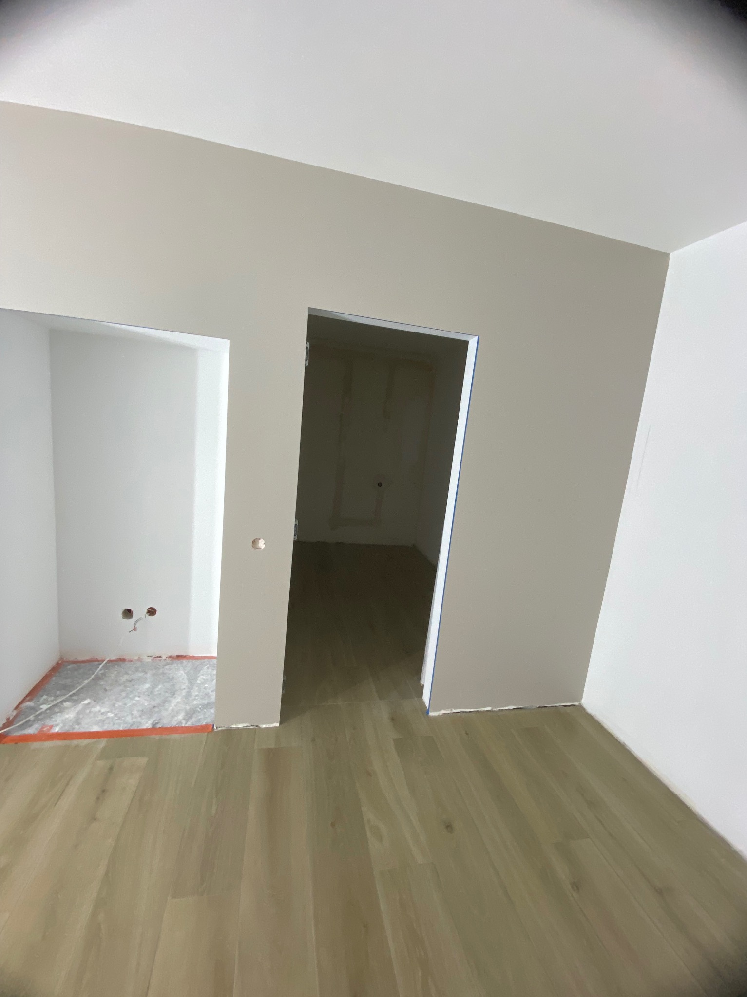 Wnętrze pokoju po remoncie: ściany pomalowane na beżowo i biało, podłoga wyłożona panelami, widoczne otwory drzwiowe i przygotowane miejsce na zabudowę.