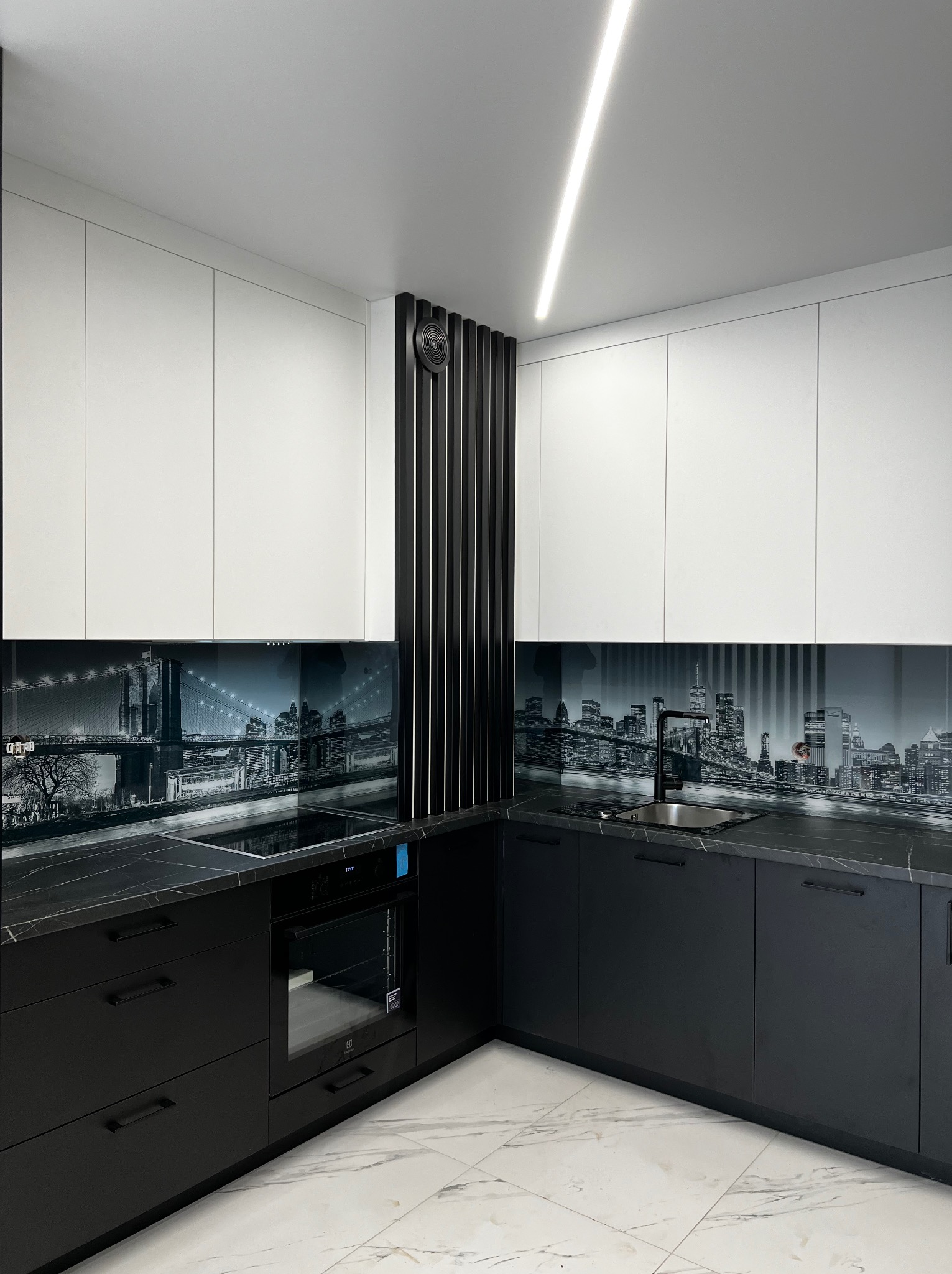 Nowoczesna kuchnia w czerni i bieli z blatem imitującym marmur, czarną armaturą i szklanym panelem z panoramą miasta