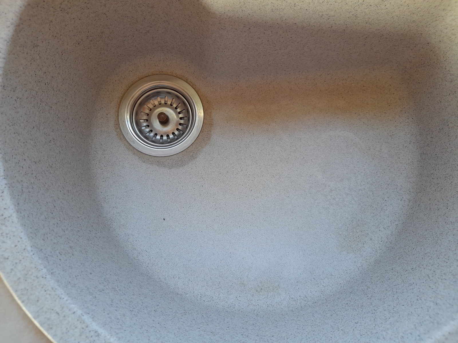 Szary zlewozmywak z metalowym odpływem, widoczne ślady użytkowania.
