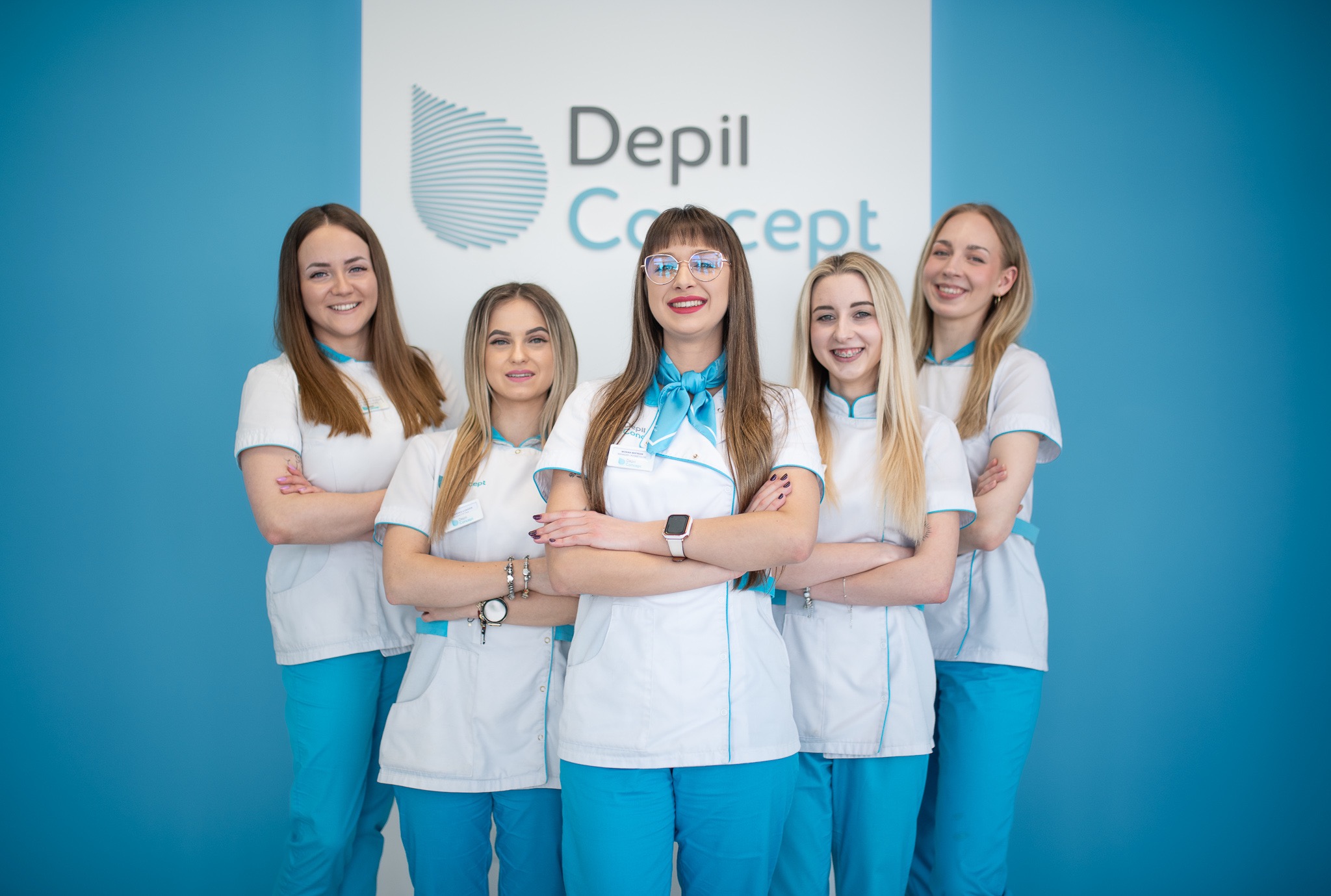 Zespół Depil Concept: Pięć uśmiechniętych kobiet w białych uniformach z błękitnymi akcentami, stojące na tle błękitnej ściany z logo firmy.