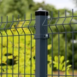 Szary panel ogrodzeniowy z pionowymi prętami i czarną nakładką na słupku, zamocowany za pomocą srebrnych śrub, na tle zieleni.