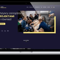 TRUST DEAL - Responsywny design strony na laptopie i smartfonie. Ekran laptopa prezentuje grupę osób przy stole, a smartfon wyświetla uproszczoną wersję strony. Ciemne tło, żółte akcenty.