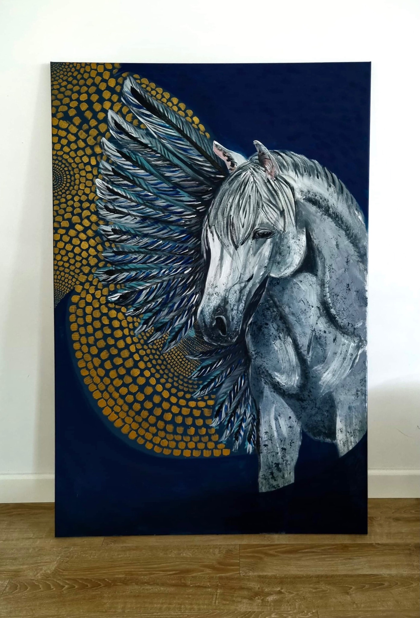 Obraz przedstawia szarego konia z błękitno-białymi skrzydłami na tle granatowej nocy z złotymi kropkami