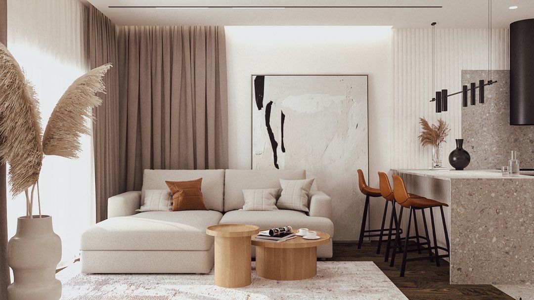 Jasny salon z sofą modułową, okrągłymi stolikami kawowymi, abstrakcyjnym obrazem na ścianie i wyspą kuchenną z hokerami w odcieniach brązu.
