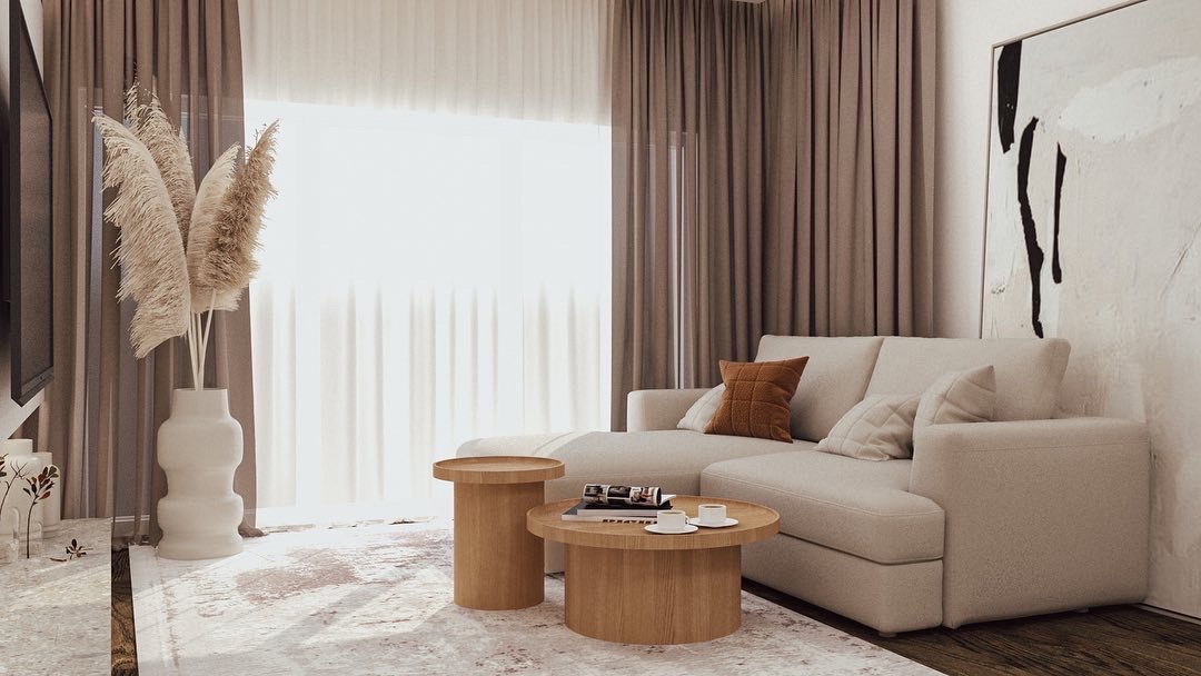 Jasny salon z narożną sofą, drewnianymi stolikami kawowymi, abstrakcyjnym obrazem na ścianie i dekoracyjną trawą pampasową w wazonie.