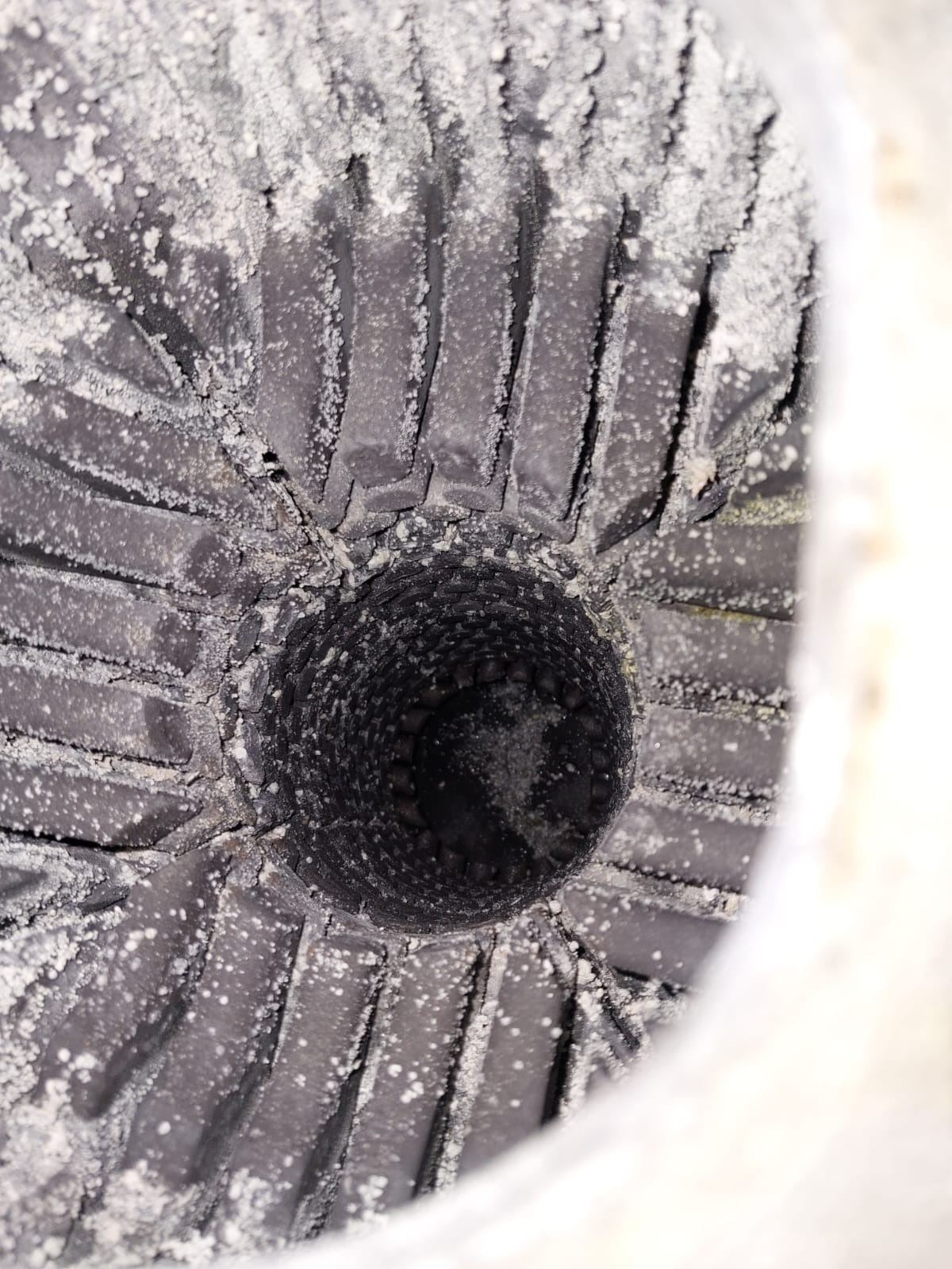 Wnętrze komina pieca gazowego, pokryte białym osadem, widok z dołu.