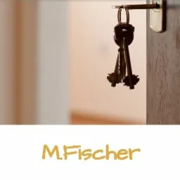 Klucze wiszące na klamce drewnianych drzwi, widok z wnętrza, jasne tło, logo firmy M.Fischer na dole.