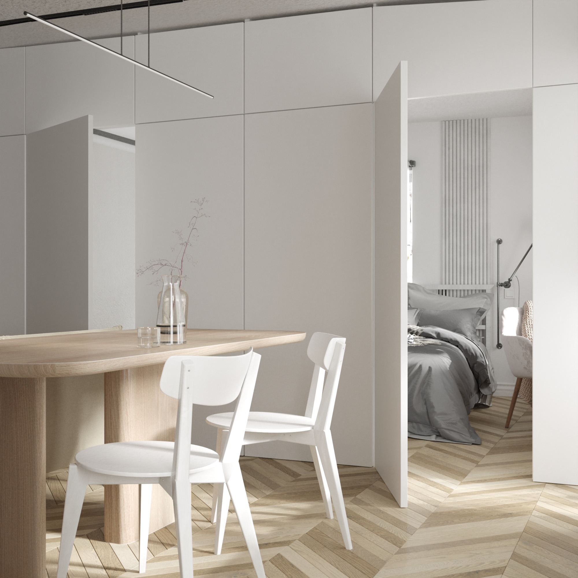 Jasne, minimalistyczne wnętrze z drewnianą podłogą w jodełkę, okrągłym stołem z drewna, białymi krzesłami i widokiem na sypialnię przez otwarte drzwi.