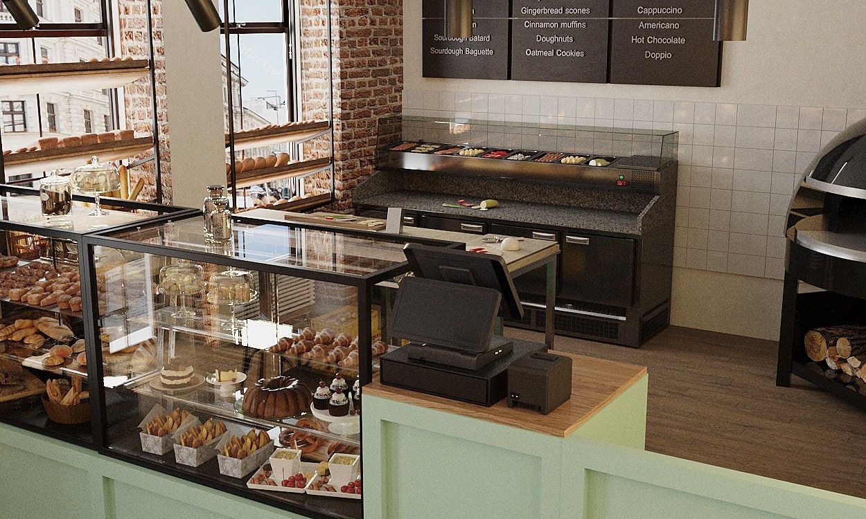 Wnętrze piekarni z przeszkloną witryną pełną pieczywa, ciast i deserów; w tle ekspozycja pieczywa na półkach przy ceglanej ścianie i stanowisko kasowe z terminalem płatniczym.