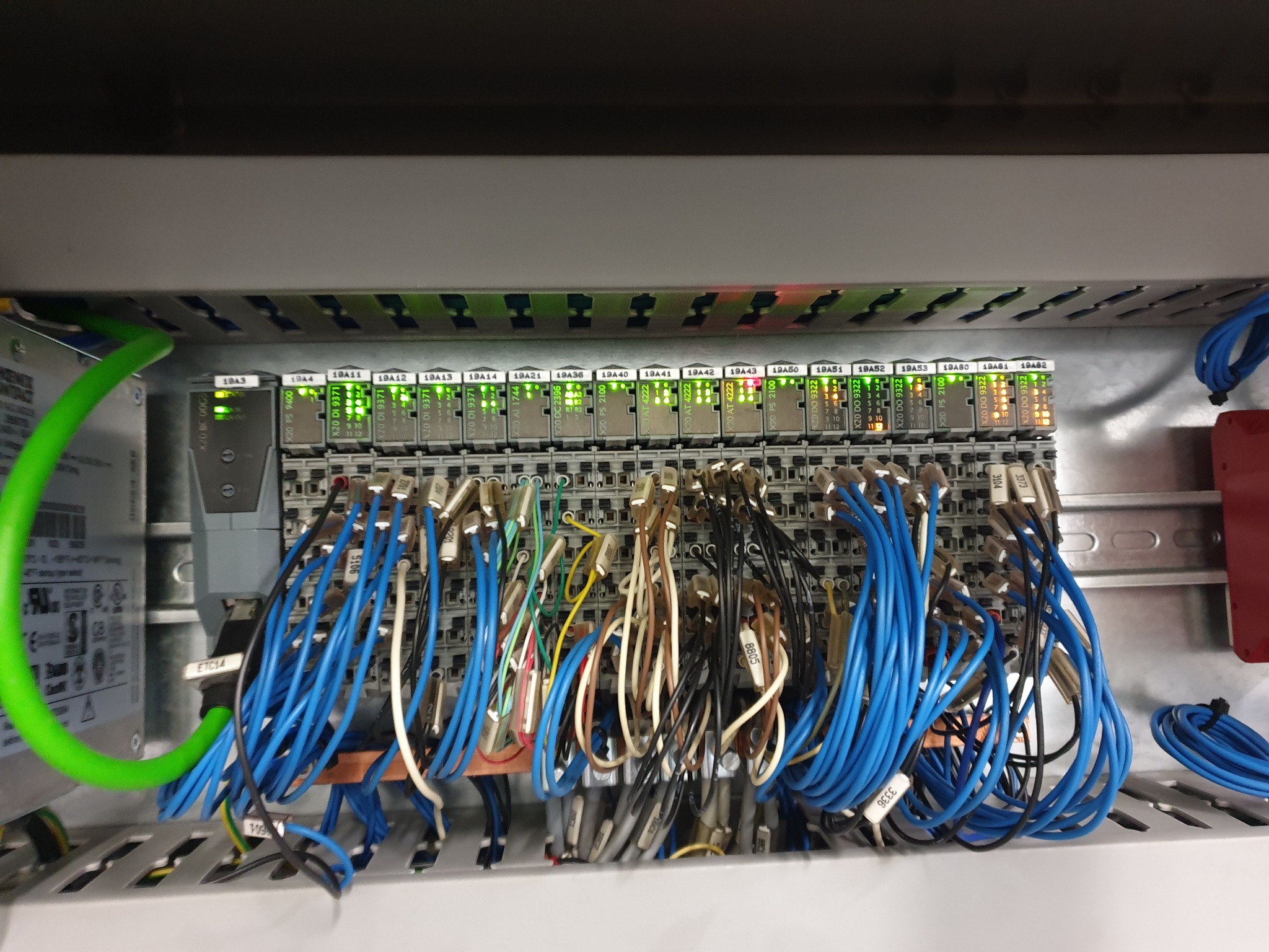 Panel sterowania automatyki przemysłowej z podłączonymi przewodami, widoczne diody sygnalizacyjne i oznaczenia modułów.