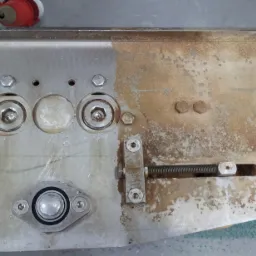 Częściowo wyczyszczona metalowa konstrukcja z widocznymi śladami zabrudzeń i różnicą w wyglądzie powierzchni po czyszczeniu, ukazująca proces usuwania zanieczyszczeń.