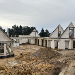 VOSBUD Vlad Balanenko - Surowy stan budowy domu z białych bloczków, widoczne ściany i otwory okienne, na pierwszym planie hałda ziemi i błoto.