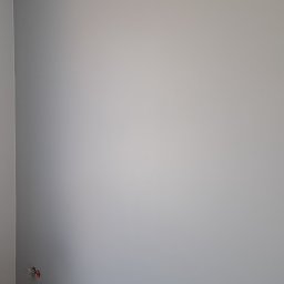 Tar-Bud - Świeżo pomalowana szara ściana w rogu pomieszczenia, widoczne puszki z farbą, walizki z narzędziami oraz wystające ze ściany kable elektryczne.