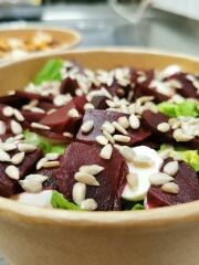 Sałatka z buraków, sera i pestek słonecznika w papierowej misce, widok z bliska, jasne oświetlenie.