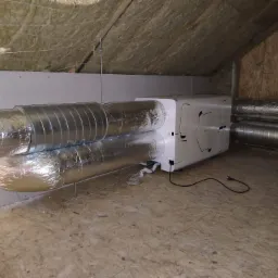 Centrala wentylacyjna z podłączonymi przewodami wentylacyjnymi w przestrzeni poddasza z izolacją wełną mineralną.