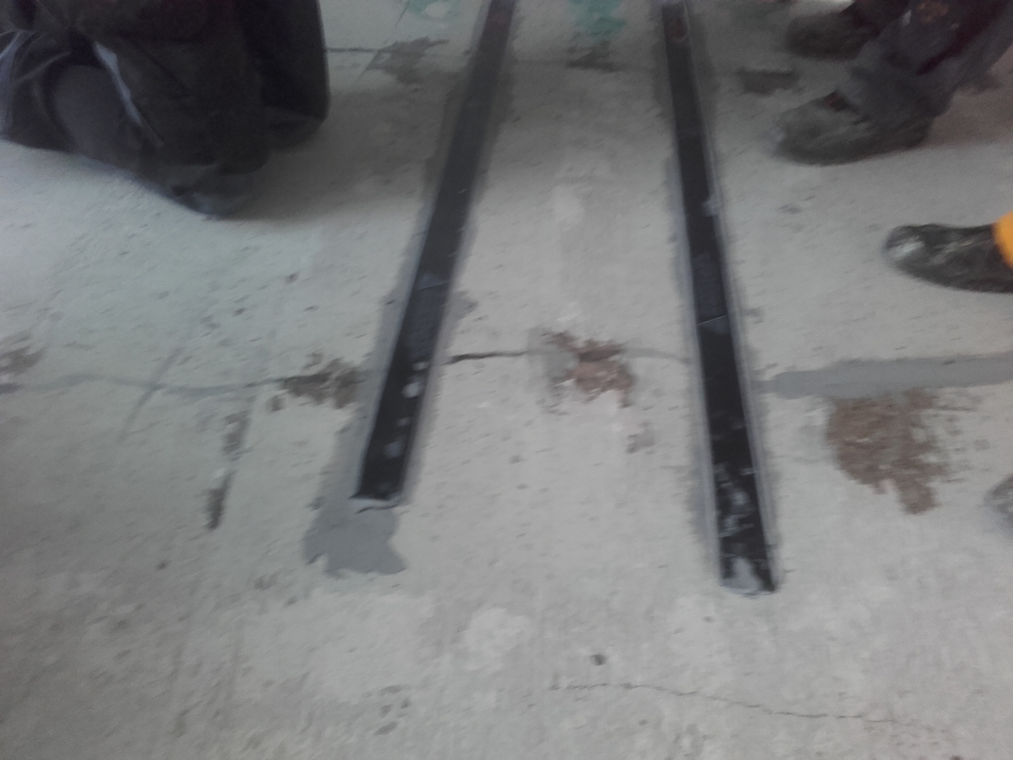 Przygotowanie podłoża pod posadzkę: widoczne listwy dylatacyjne i zalane szpary w betonie, fragmenty obuwia roboczego w tle.