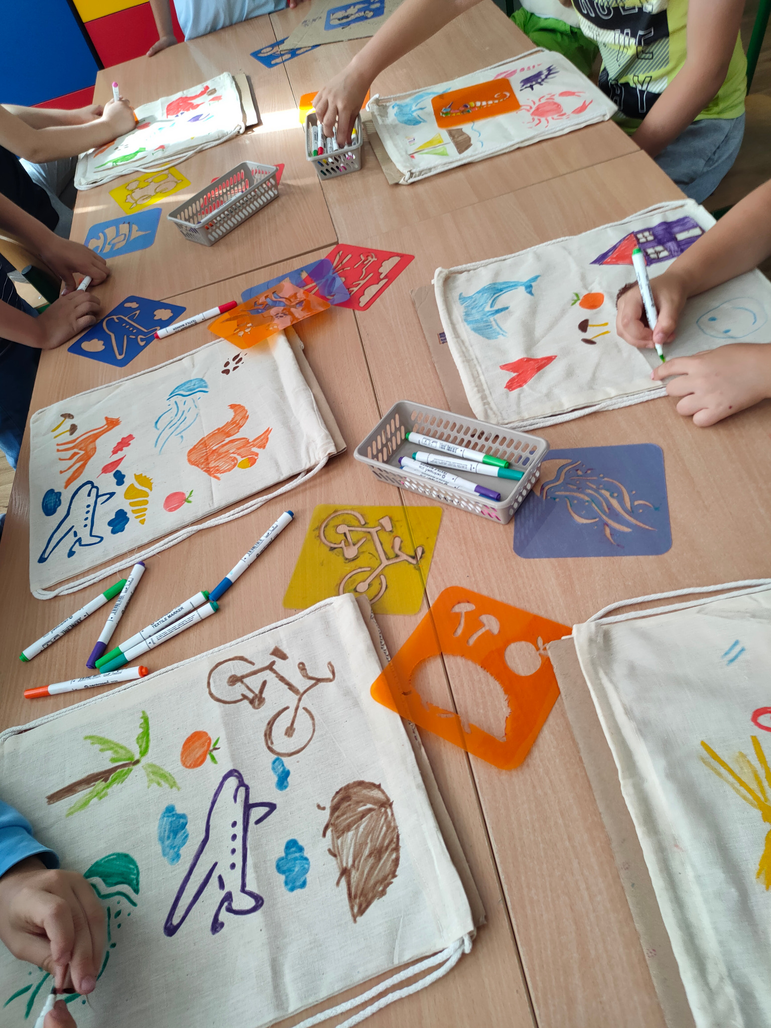 Dzieci w Błoniu dekorują bawełniane torby markerami i szablonami z motywami morskimi, zwierzętami i roślinami, podczas warsztatów kreatywnych.