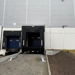 ML Pro Group Łukasz Marszał - Rampa przeładunkowa z kostki brukowej przed magazynem, widoczne czarne uszczelnienia dokowe i fragment ściany budynku z oznaczeniem T4.