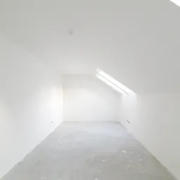 Puste, białe poddasze z oknem dachowym, ściany i podłoga przygotowane do dalszych prac wykończeniowych, widoczne wystające przewody elektryczne.