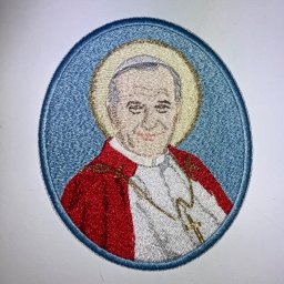 Studio RS Haft Komputerowy - Owalna naszywka z wizerunkiem Jana Pawła II, wykonana techniką haftu maszynowego. Detaliczne odwzorowanie postaci, aureola i szaty w żywych kolorach na jasnym tle.
