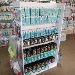 Półka sklepowa z dekoracjami urodzinowymi: świeczki w kształcie cyfr w złotym, srebrnym i niebieskim kolorze, oraz balony foliowe z cyframi, w opakowaniach na tle innych akcesoriów imprezowych.