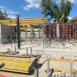 ARMBET Vasyl Bersan - Przygotowanie do wylania fundamentów z użyciem szalunków systemowych, widoczne zbrojenie i podpory, w tle drzewa i błękitne niebo.