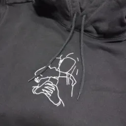 Czarna bluza z kapturem z białym, minimalistycznym haftem przedstawiającym osobę trzymającą telefon.