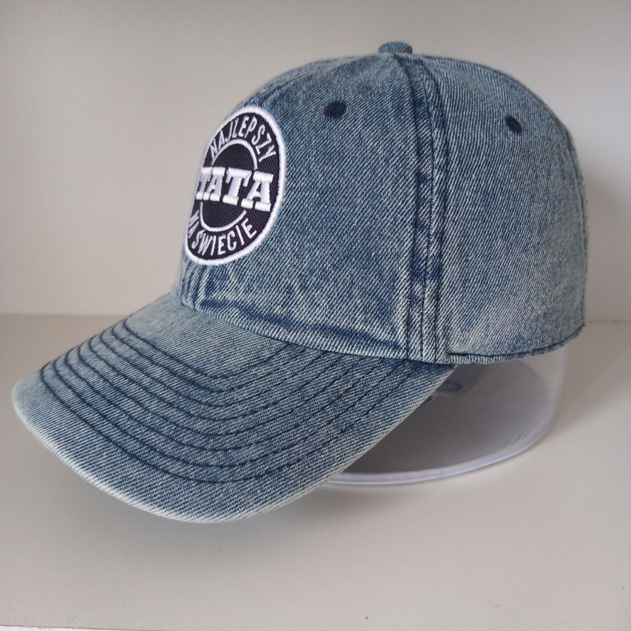 Dżinsowa czapka z daszkiem z naszywką z napisem 'Najlepszy Tata w Świecie' na białym tle.