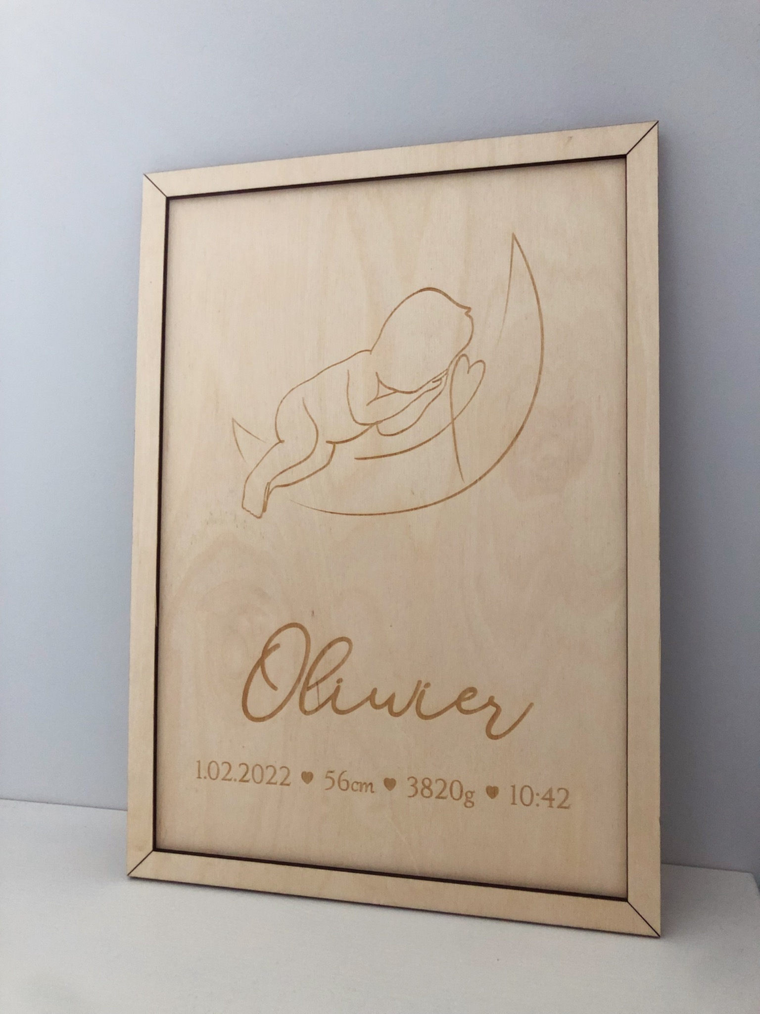 Drewniana tabliczka z wygrawerowanym wizerunkiem śpiącego dziecka na księżycu, imieniem Olivier oraz datą, wagą i wzrostem urodzenia.