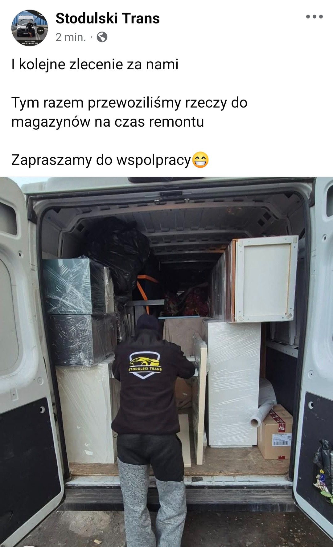 Wnętrze busa firmy Stodulski Trans załadowane meblami i przedmiotami zabezpieczonymi folią stretch, widok z tyłu na pracownika w bluzie z logo firmy.
