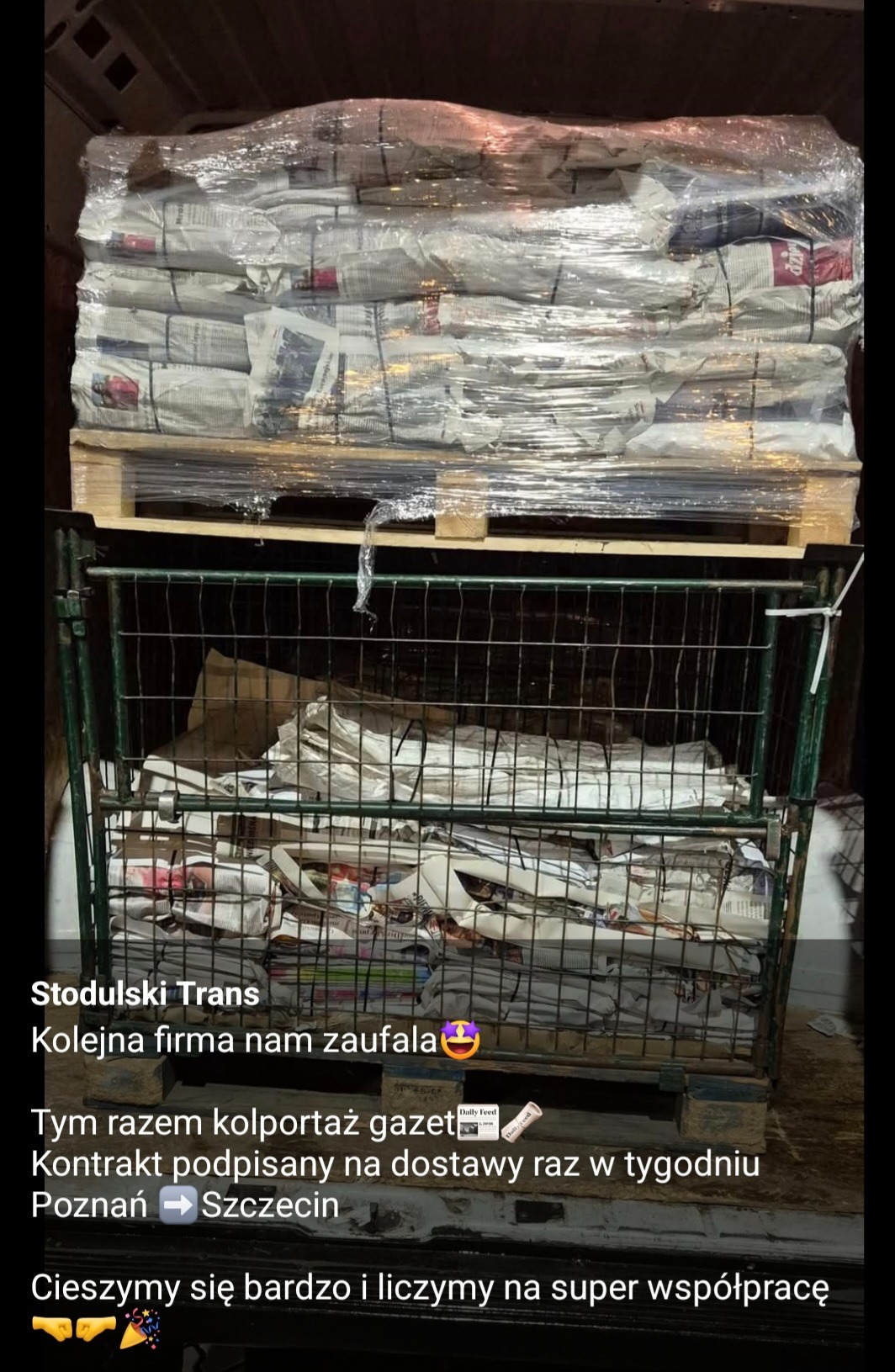 Palety z zapakowanymi gazetami w folii stretch i metalowej klatce, przygotowane do transportu, widok z wnętrza pojazdu.