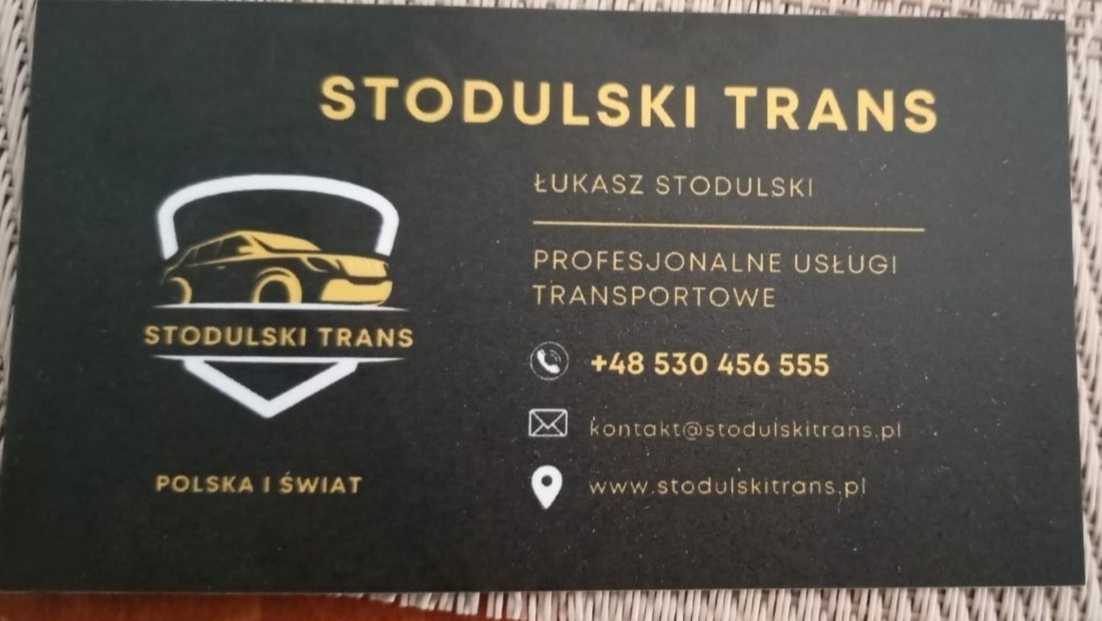 Wizytówka firmy Stodulski Trans z logo przedstawiającym samochód oraz informacjami kontaktowymi: imię, numer telefonu, adres e-mail i strona internetowa.
