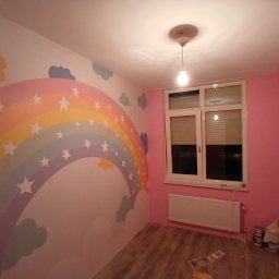 Fende Schilderwerken - Pokój dziecięcy po malowaniu: tęcza z gwiazdami na ścianie, różowe ściany, białe okno i grzejnik. Widoczne akcesoria malarskie na podłodze.