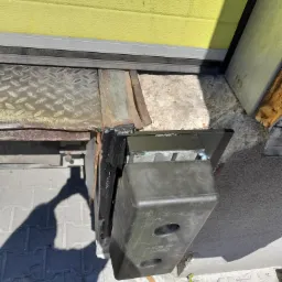 Szczegółowe ujęcie dolnej części bramy przemysłowej z widocznym mechanizmem i elementami montażowymi, z napisem 'Made in Poland' na obudowie.