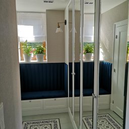 Dmytro Abramchuk - Wnętrze przedpokoju z zabudową wnękową: siedzisko z granatową tapicerką pod oknem, szafa z lustrzanymi drzwiami, wzorzysta podłoga.